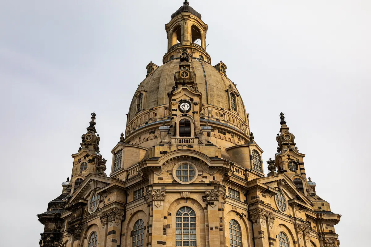 The stone dome of the Frauenkirche in Dresden with a gilded cross and four small corner towers.